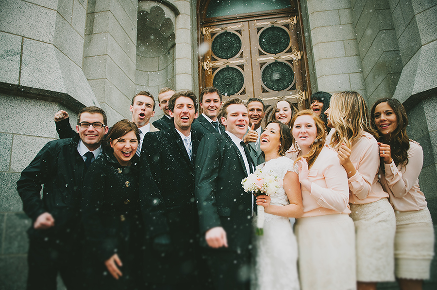 Snowy winter wedding with a laughing bridal party bundled up.