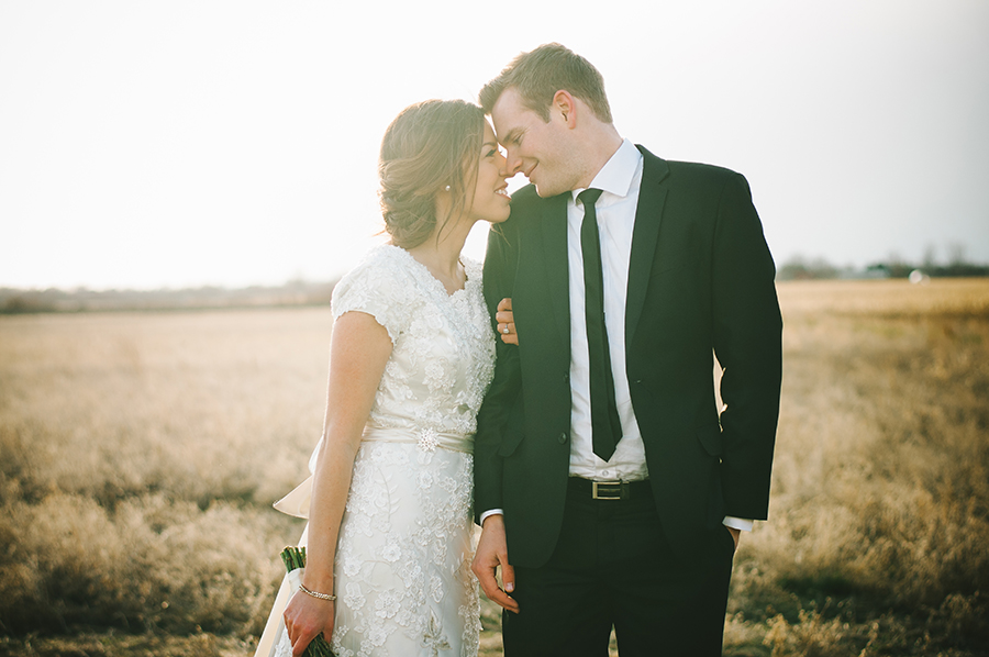 Warm sunshine falling over the bride & groom in a soft yellow field.