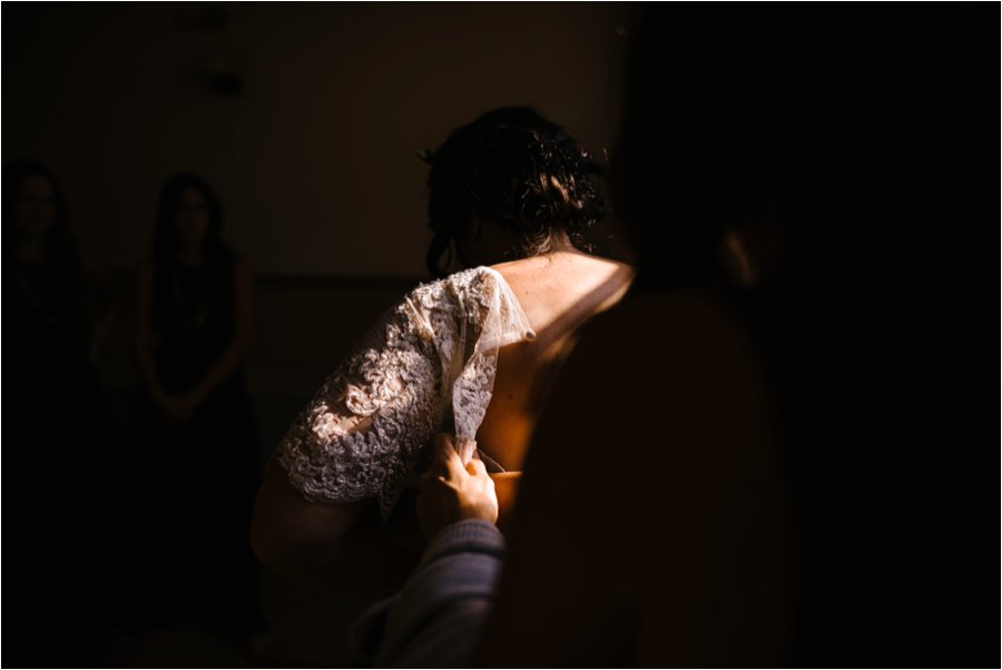 Moody wedding photo of bride getting dresses on her wedding day.