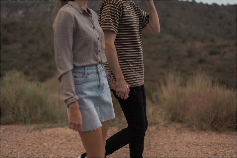 Photo of a couple holding hands, walking in the desert.  Shot on film