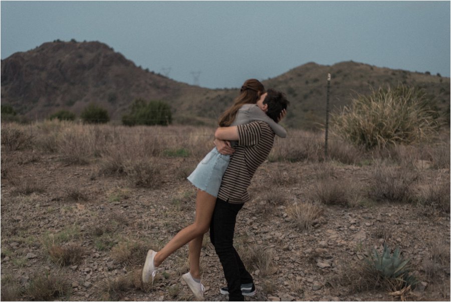 Lovers on a roadtrip in the Arizona desert.  Guy picking his girl up and swinging her around