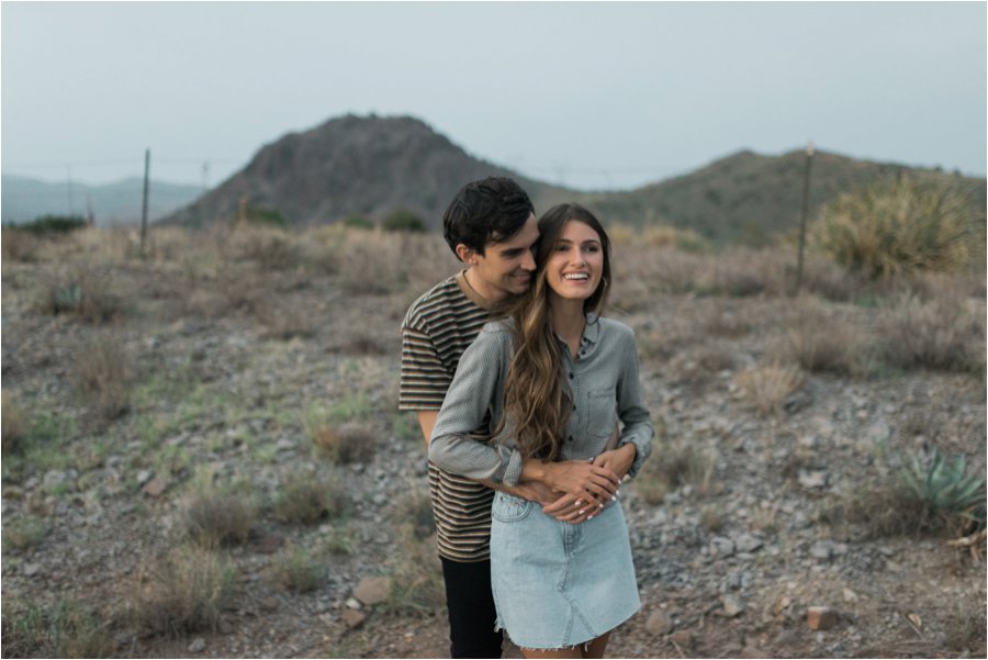 Cute couple cuddling in the desert at dusk.